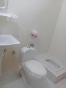 a white bathroom with a toilet and a sink at Benazir Hotel Kalash 