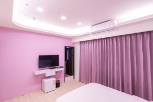 a bedroom with purple walls and a bed and a tv at 幾何拼圖民宿 in Magong