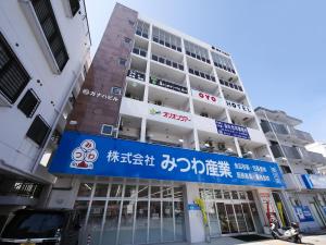 a building with a blue sign in front of it at Chura Gahna House Tsubogawa Naha in Naha