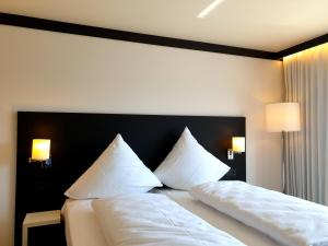 1 dormitorio con 2 camas con sábanas y almohadas blancas en ILL Hotel by WMM Hotels en Illertissen
