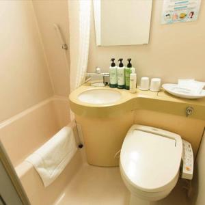 a small bathroom with a toilet and a sink at Hotel AreaOne Miyazaki in Miyazaki