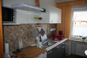 eine Küche mit weißen Schränken, einem Waschbecken und einem Fenster in der Unterkunft Ferienwohnungen Alt in Naumburg