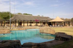 a pool in front of a building with a building at Thabaledi Game Lodge in Brits