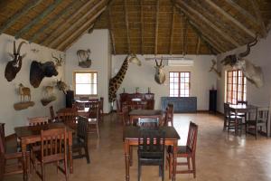 a dining room with tables and giraffe heads on the wall at Thabaledi Game Lodge in Brits
