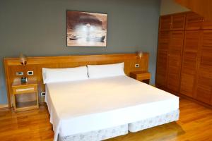 Schlafzimmer mit einem großen weißen Bett mit einem Kopfteil aus Holz in der Unterkunft Hotel Alda El Suizo in Ferrol