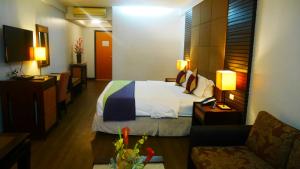 Circle Inn Hotel and Suites Bacolod في باكولود: غرفه فندقيه بسرير واريكه
