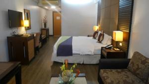 Habitación de hotel con cama y sofá en Circle Inn Hotel and Suites Bacolod, en Bacolod