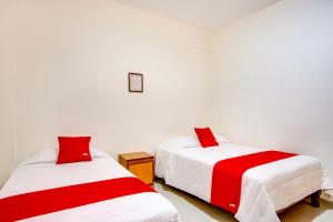 科利馬的住宿－Hotel La Estancia，配有红色和白色床单的客房内的两张床
