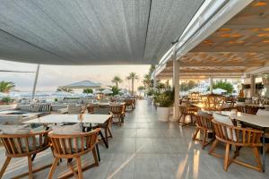 um restaurante com mesas e cadeiras e vista para o oceano em King Jason Protaras - Designed for Adults em Protaras