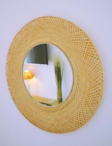 a w rattan mirror with a vase in a room at Hôtel & Espace Bien-être La Maison du Lierre in Biarritz