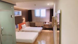 a hotel room with two beds and a desk at 7Days Premium Chongqing Airport Light Rail Huixing Station Branch in Chongqing