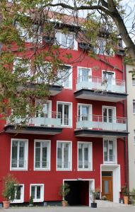 um edifício vermelho com janelas brancas e uma árvore em Deluxe Apartment 35qm im Design Hotel Vosteen em Nuremberga