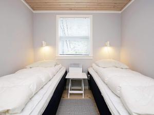 two beds in a room with a table and a window at 6 person holiday home in Væggerløse-By Traum in Marielyst +23 photos