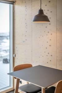 a table and chairs in a room with a wall at Aska, Modern Cabin in Myvatn