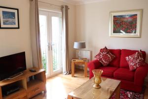 sala de estar con sofá rojo y TV en Kilchurn Suites, en Loch Awe
