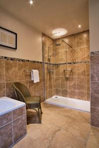 y baño con ducha, bañera y silla. en Kilchurn Suites en Loch Awe