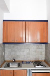 una cocina con armarios de madera y fregadero en Coralli Apartments en Pefki Rhodes