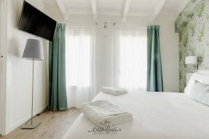 a bedroom with a white bed with a flat screen tv at CASA BACI - Soggiorno nel Gusto in Colà di Lazise