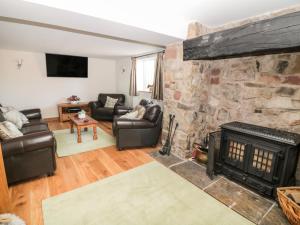 a living room with a stone fireplace and leather furniture at The Farmhouse in Biddulph