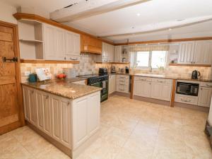 a large kitchen with white cabinets and appliances at The Farmhouse in Biddulph