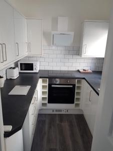 eine Küche mit weißen Schränken und einer schwarzen Arbeitsplatte in der Unterkunft Rock Salt Studios in Blackpool