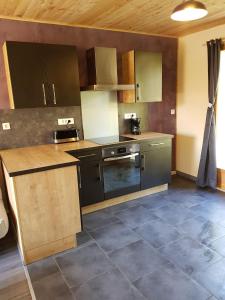 a kitchen with black appliances and wooden cabinets at maison indépendante in Saint-Amand-en-Puisaye