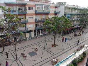 a courtyard with tables and a tree in front of a building at Paula Bela by Garvetur in Quarteira