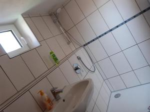 a white tiled bathroom with a sink and a window at ATELIER IM STADTGARTEN direkt in Rottweil in Rottweil +10 photos