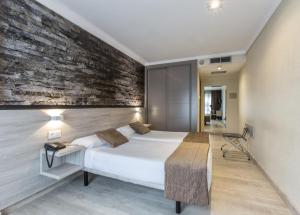 sypialnia z łóżkiem i ceglaną ścianą w obiekcie Hotel Alda San Carlos w Santiago de Compostela