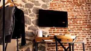 TV en una pared de ladrillo con mesa y silla en Hôtel Zadig en Aurillac