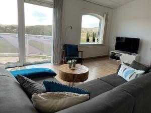 a living room with a gray couch and a table at Strandappartement Duynblick in Julianadorp