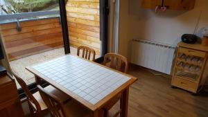 uma mesa e cadeiras numa cozinha com uma janela em appartement chaleureux avec terrasse ensoleillée 2 étoiles em Le Mont-Dore