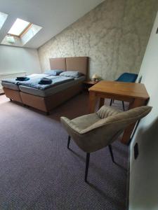 ein Schlafzimmer mit einem Bett, einem Tisch und einem Stuhl in der Unterkunft Penzion Bily Beranek in Kadaň