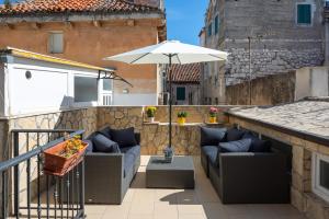 un patio con 2 sofás y una sombrilla en Awesome Stone House, en Split