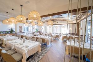 a restaurant with white tables and chairs and chandeliers at PortAventura Hotel PortAventura - Includes PortAventura Park Tickets in Salou