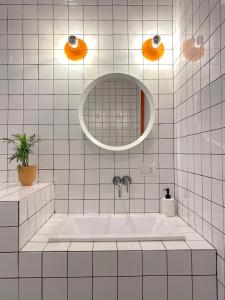 ミラノにあるCeruleo apartmentの白いタイル張りのバスルーム(バスタブ、鏡付)