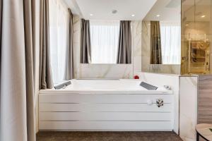 La salle de bains est pourvue d'une baignoire blanche et de fenêtres. dans l'établissement Best Western Hotel Rocca, à Cassino