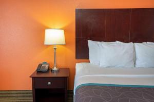 a hotel room with a bed and a lamp on a table at La Quinta by Wyndham Houston IAH Bush Intl Airport E in Humble