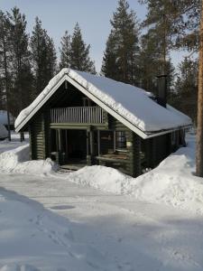 Cabaña de madera con nieve en el techo en Levihaukka 10 en Sirkka