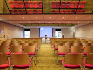 an empty lecture hall with chairs and a person in the background at Novotel Paris La Defense Esplanade in Courbevoie