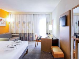 a hotel room with a bed and a living room at Novotel Lisboa in Lisbon