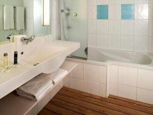 a white bathroom with a tub and a sink at Novotel Lisboa in Lisbon