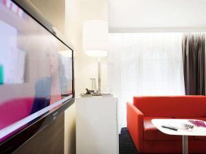 a living room with a red couch and a tv at Mercure Lille Centre Grand Place in Lille