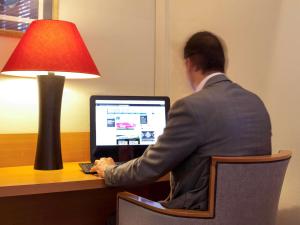 a man in a suit sitting at a desk with a computer at ibis Biarritz Anglet Aéroport in Anglet