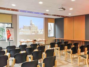 a conference room with chairs and a large screen at ibis Le Puy-en-Velay Centre in Le Puy-en-Velay