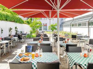 a patio with tables and chairs and an umbrella at ibis München City Nord in Munich