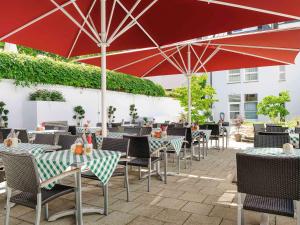 un patio al aire libre con mesas, sillas y sombrillas en ibis München City Nord en Múnich