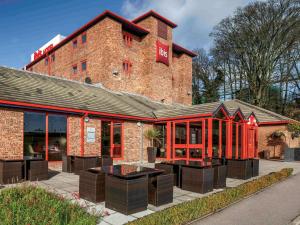 un edificio de ladrillo con mesas delante en ibis London Luton Airport en Luton