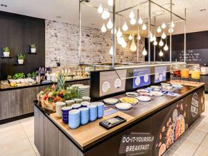 a restaurant with a counter with food on it at Novotel Frankfurt City in Frankfurt