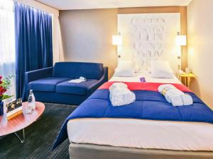 ein Hotelzimmer mit einem großen Bett und einem blauen Sofa in der Unterkunft Mercure Rennes Centre Parlement in Rennes